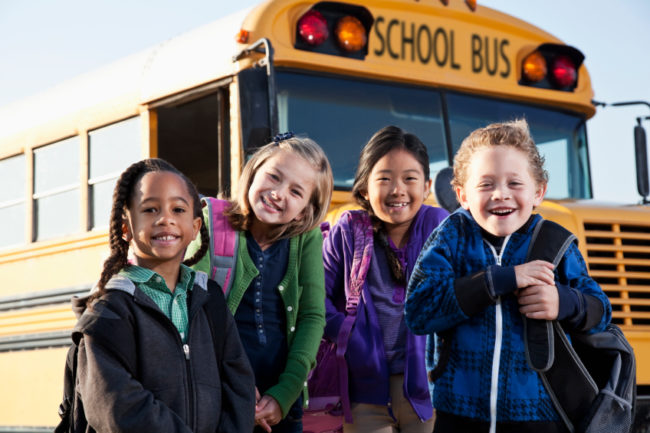 Children standing outside school bus